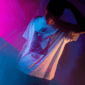 Person in a limited edition graphic tee under moody neon lighting, symbolizing exclusive merch and underground culture